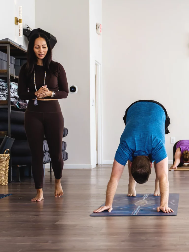 Student in downward facing bend with teacher guiding