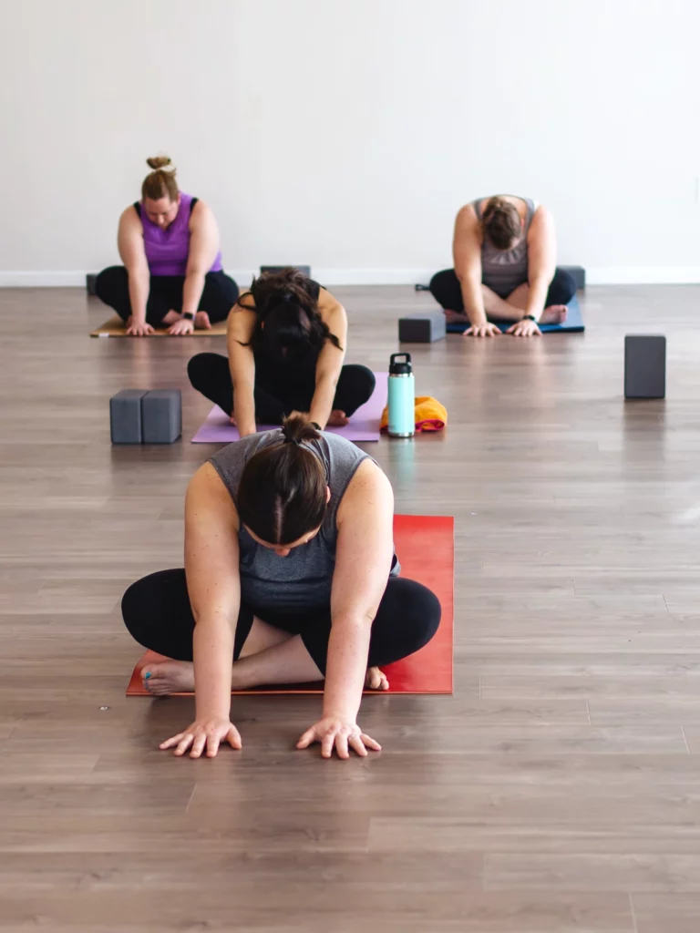 Students seated crosslegged and bending forward to stretch